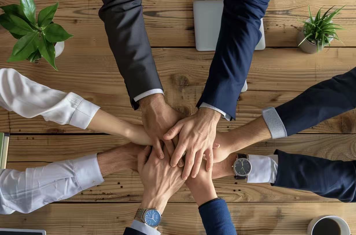 Business team joining hands around an office table