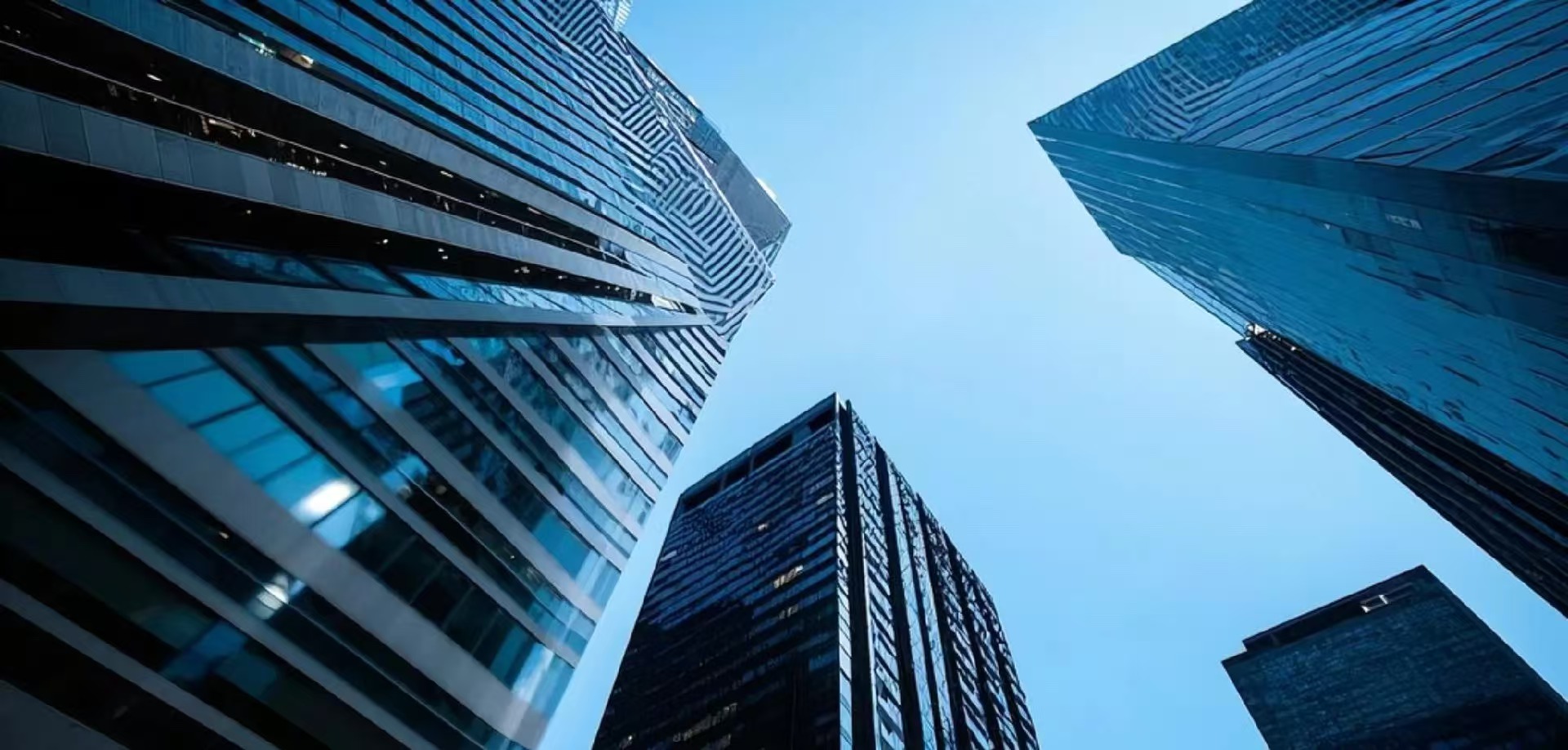 Modern office towers viewed from below against a blue sky